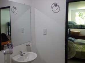 A bathroom with a sink, mirror, and two towel rings on the wall.