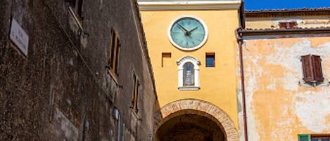 Una estrecha calle adoquinada con edificios históricos, una torre del reloj y un pasaje en arco.