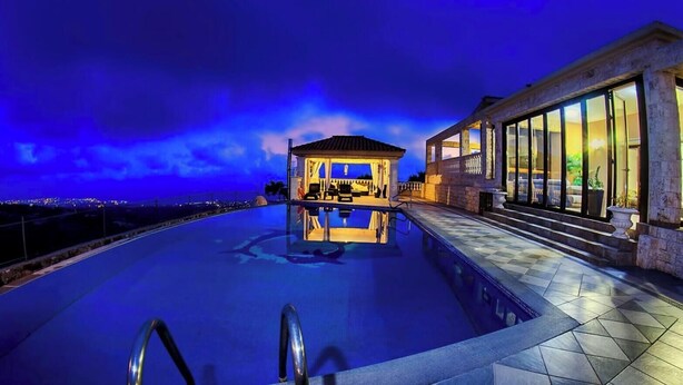 A swimming pool with a gazebo, a stone building with large windows, and a view of the city at dusk. - Elegant Huge Villa Large Pool, Ideal For Weddings (Kathikas)