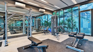 A modern gym with various exercise equipment, large windows, and a view of outdoor stairs. - Bo401 - 2 Bdr Condo With Sea View, Ao Nang Beach (Krabi)