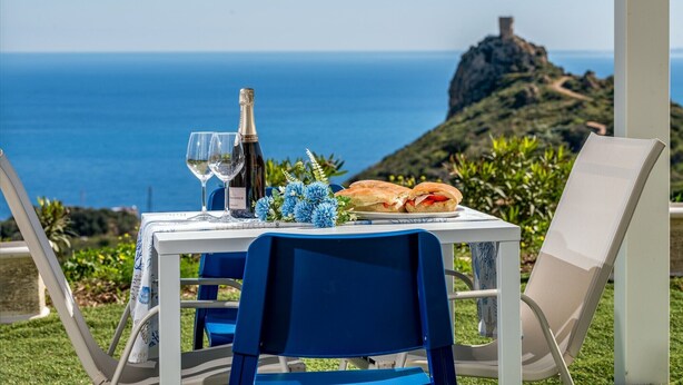 A table set with a bottle of champagne, two glasses, a plate with a sandwich, and blue flowers. - Villa Holidays Vista Torre Bennistra in Scopello (Castellammare del Golfo)