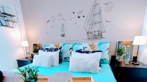 Un dormitorio moderno con cama, almohadas, una bandeja con una planta y decoración en la pared.