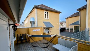 A wooden deck with a hammock, a table, and chairs, overlooking a residential area. - Stavanger Bnb at Nicolas 11 (Stavanger)