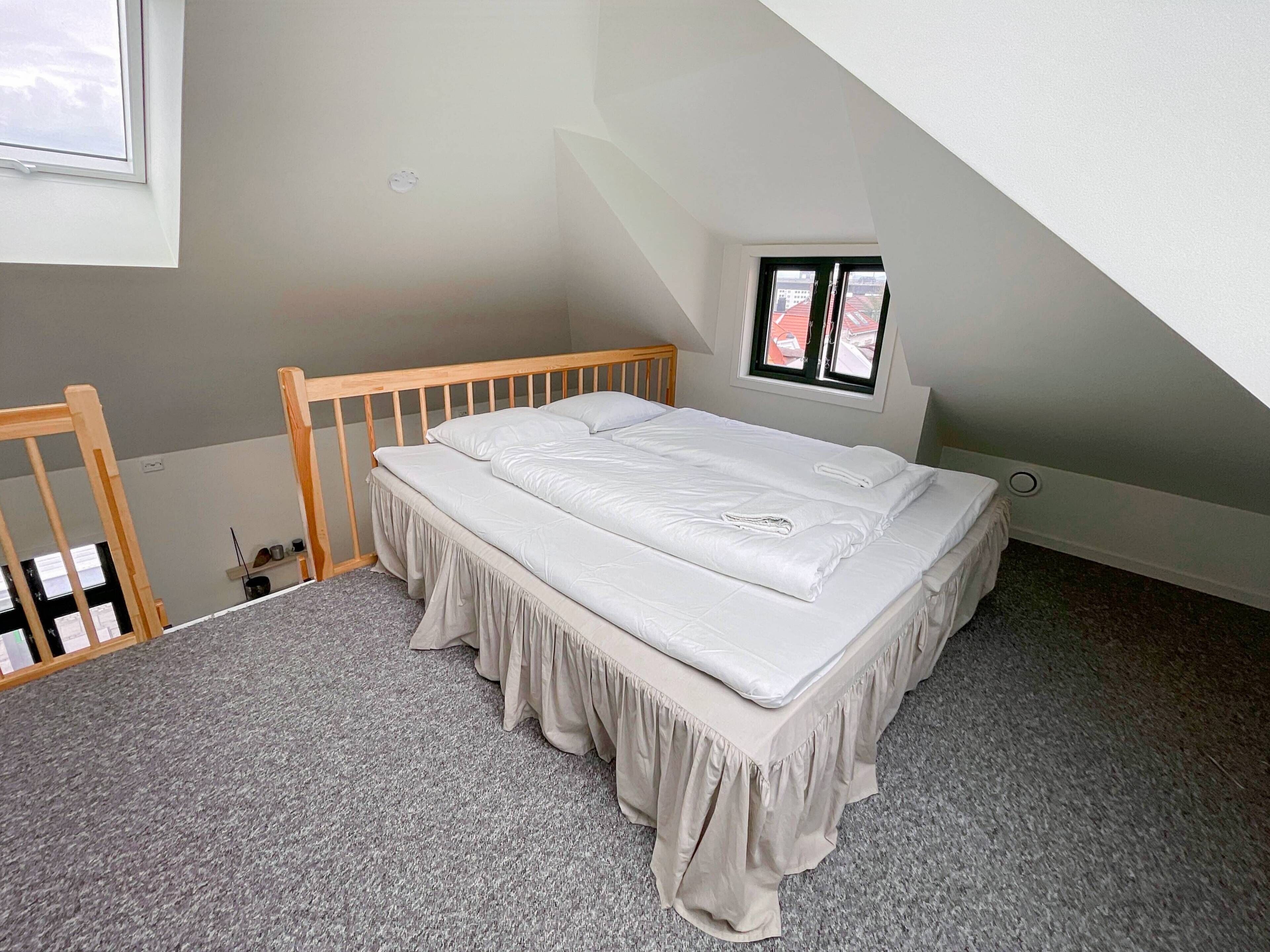 A bedroom with a single bed, a window, and a sloped ceiling.