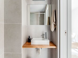 Ein modernes Badezimmer mit einem weißen Waschbecken, einem Spiegel und einem Wandhandtuch.