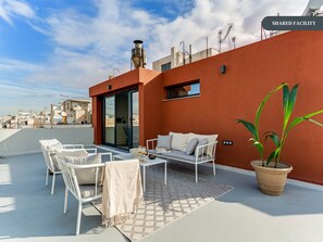 A rooftop terrace with white furniture, a potted plant, and a view of the cityscape. - Sanders Port - Endearing Studio Near Piraeus Port (Piraeus)