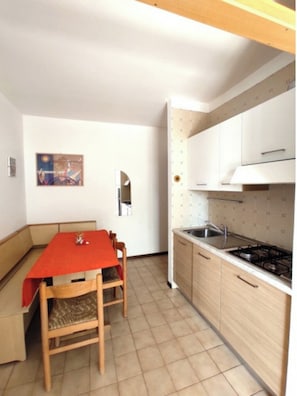 Une cuisine de taille réduite comprenant une table et des chaises, un fourneau et un évier.