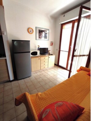 Une chambre comprenant un lit, une petite kitchenette, un réfrigérateur, un four à micro-ondes et un téléviseur.