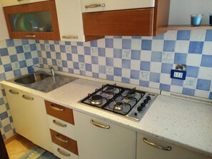 Une cuisine de taille réduite équipée d’une cuisinière à gaz, d’un évier et d’un four à micro-ondes.