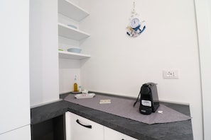 Enjoy a modern kitchen with a coffee machine, wall-mounted clock, and ample storage.