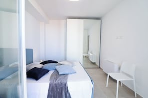 Ein modernes Schlafzimmer mit Bett, Stuhl und Spiegel.