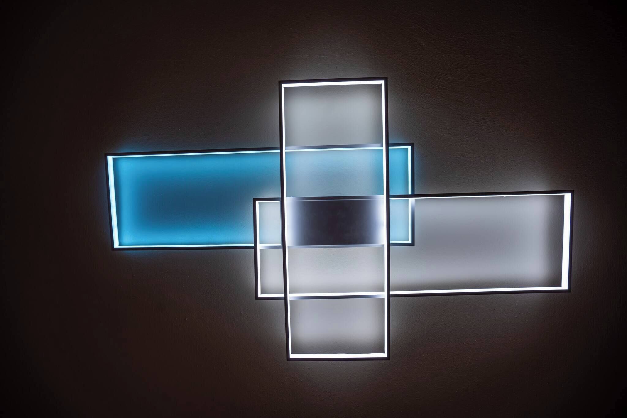 A wall with a geometric light fixture.