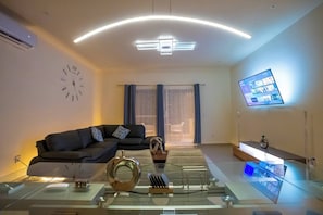 Un salon moderne comprenant un canapé, une table basse, un téléviseur et des objets de décoration.