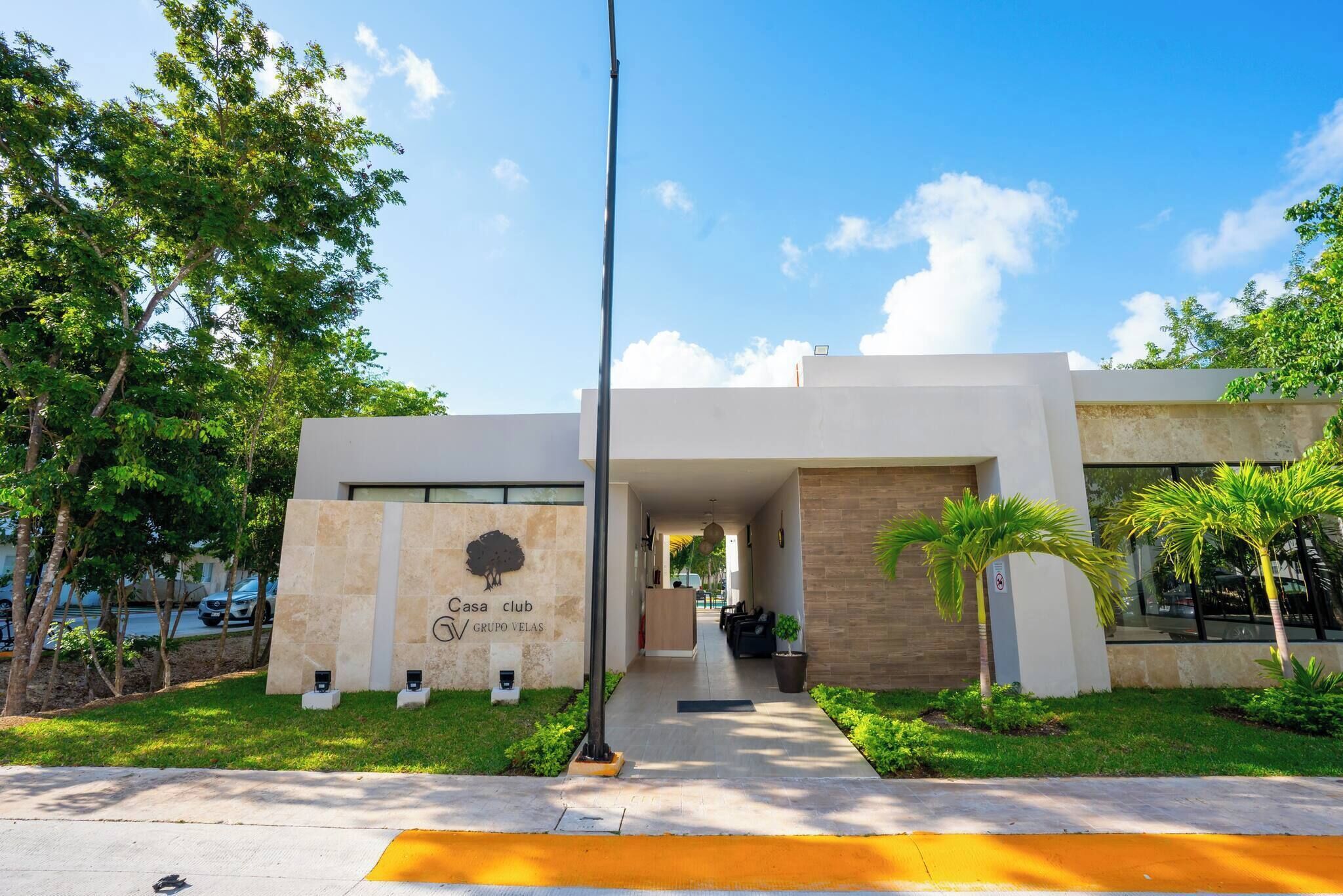 A modern building with a reception area, a sign reading 'Casa Club Grupo Veleas,' and a pathway leading to the entrance.