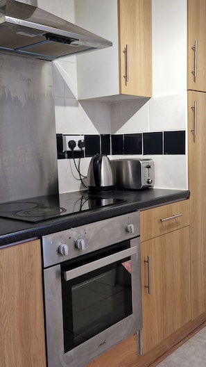 Une cuisine équipée d’une cuisinière, d’un four, d’un grille-pain et de meubles de rangement en bois.