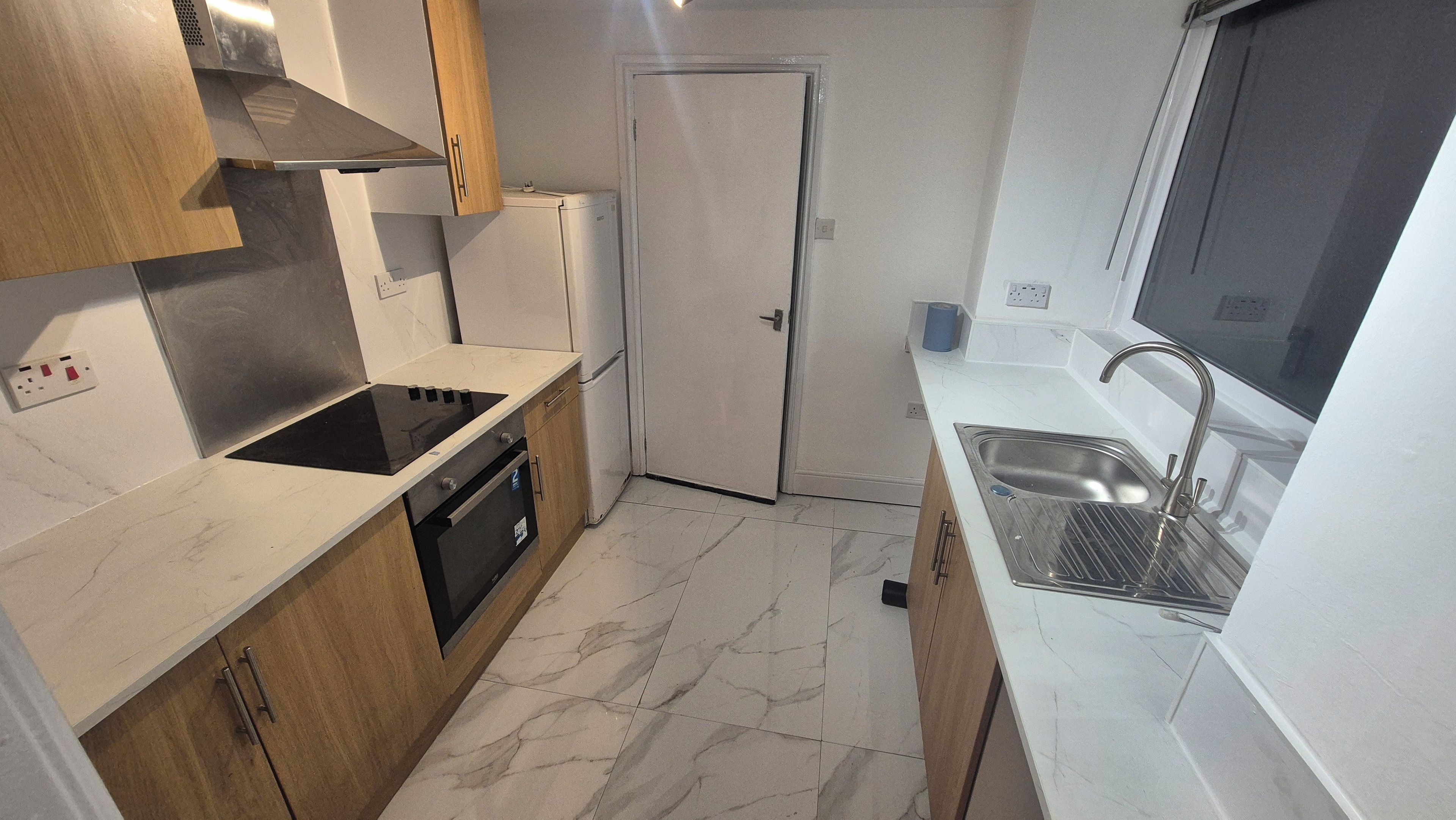 Cocina compacta con horno integrado, estufa y lavabo.