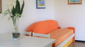 A room with a white table, orange sofa, and a potted plant.