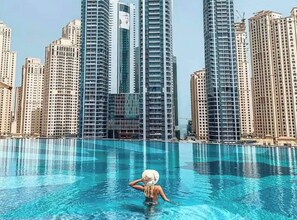 Eine Person im Pool, im Hintergrund hohe Gebäude.