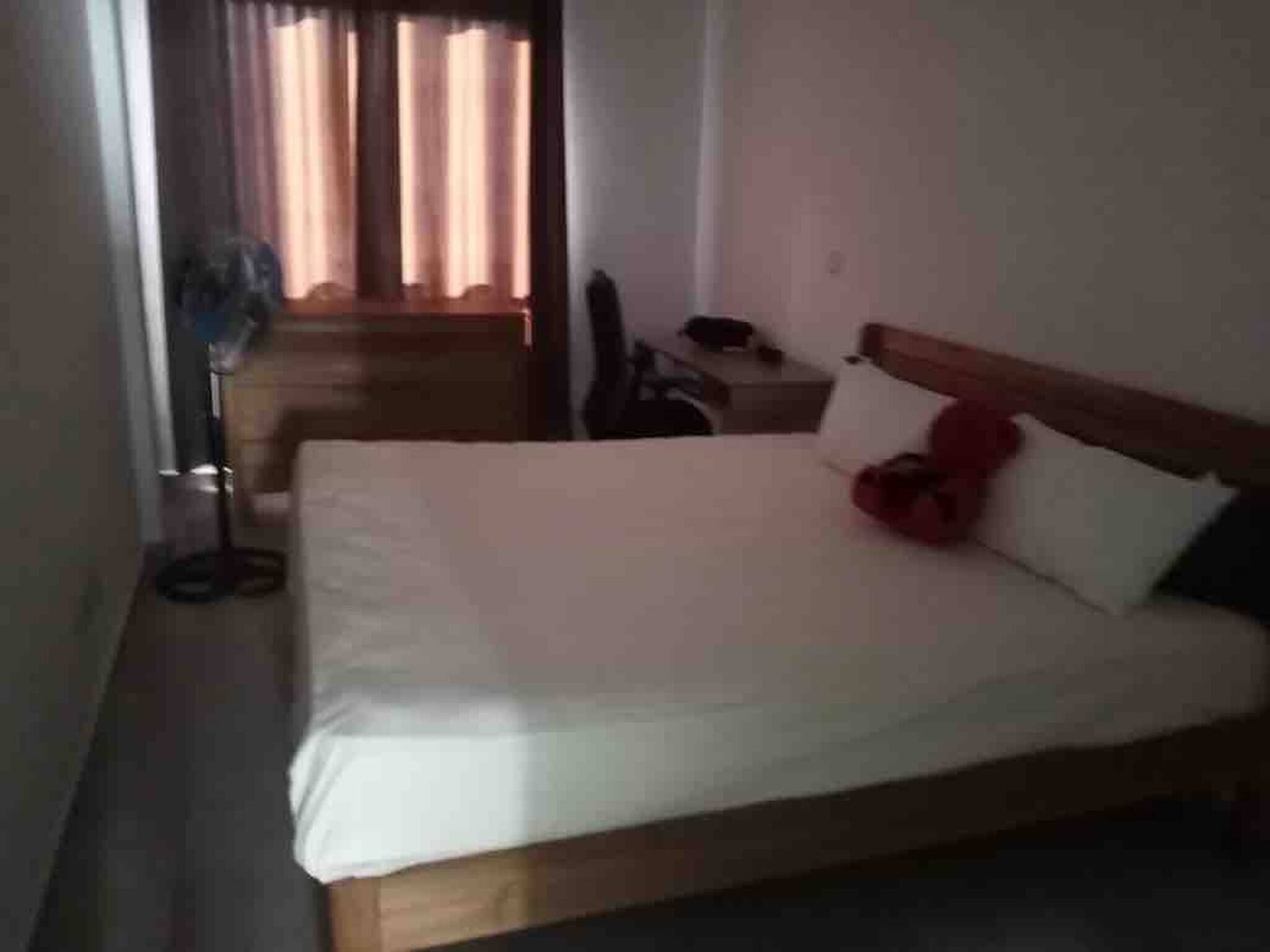 Una habitación de hotel con cama, mesita de noche, escritorio y una silla.