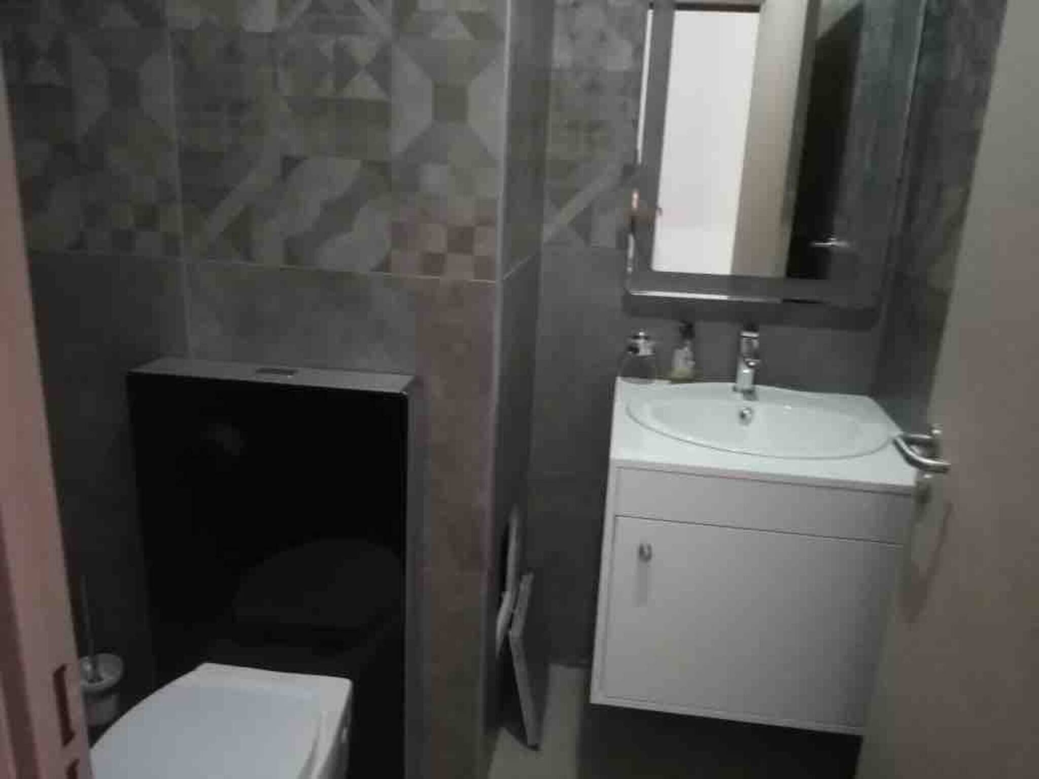 A bathroom with a toilet, sink, and mirror.