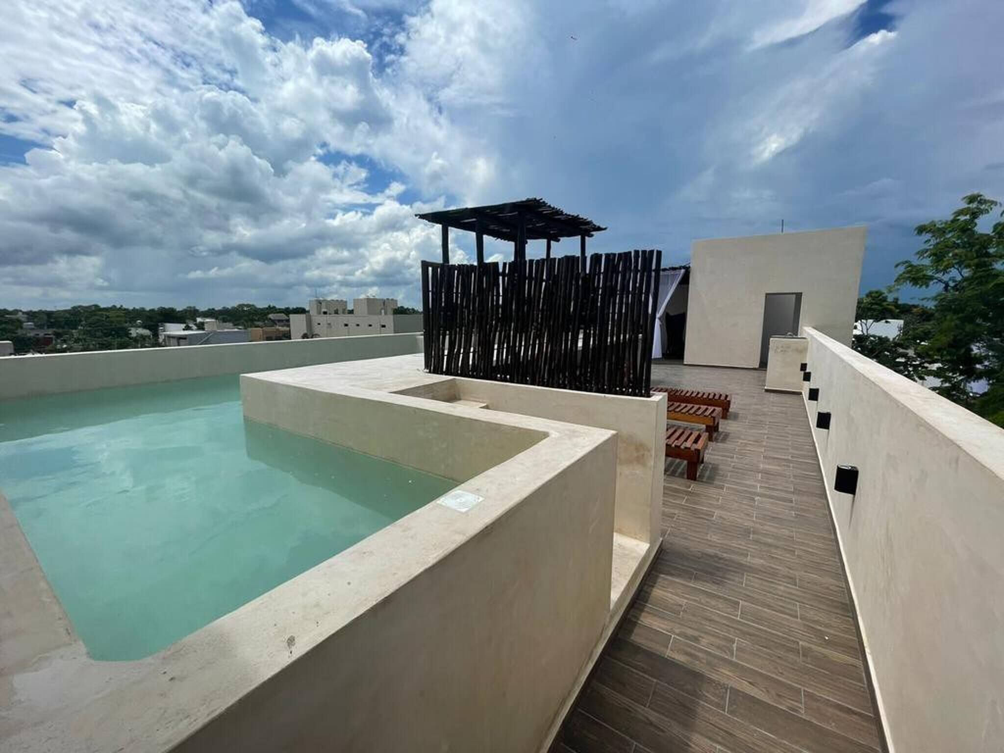 Un espace piscine aménagé sur le toit, offrant une vue dégagée sur le ciel et les bâtiments environnants.