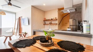 A modern kitchen with a wooden table, black coasters, a potted plant, and a stainless steel refrigerator. - Magical Ph In Town Wprivate Rooftop Glass Tub (Tulum)