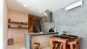 A modern kitchen with a built-in island, stainless steel appliances, and a grey concrete wall. - Magical Ph In Town Wprivate Rooftop Glass Tub (Tulum)