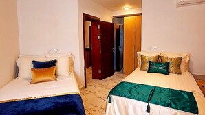 A hotel room with two beds, a ceiling light, a door, and a wall-mounted air conditioning unit. - Modern Design, Mediterranean Vibes Porto Said (Al-Manasrah)