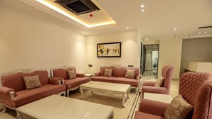 A spacious living room with red sofas and white tables, a painting on the wall, and a modern ceiling design. - DAYAL GATEWAY (Lucknow)