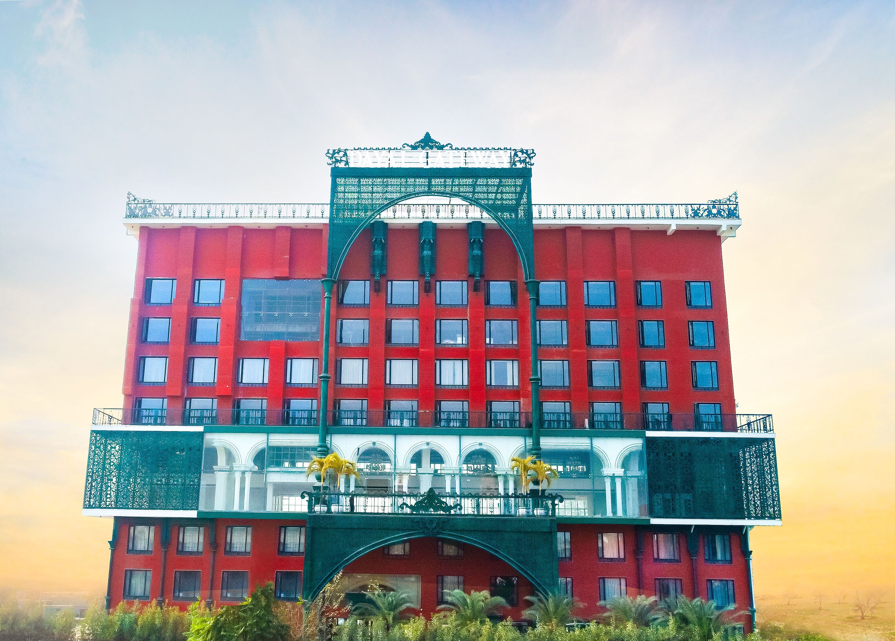 Un edificio rosso con molte finestre e un arco verde all'ingresso.
