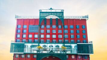 Un edificio rojo con varias ventanas y un arco verde en la entrada.