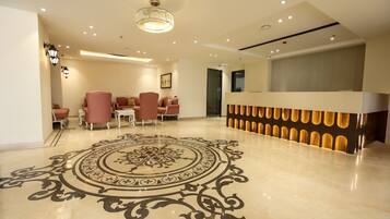 A modern lobby with a polished floor, a reception desk, and seating area.
