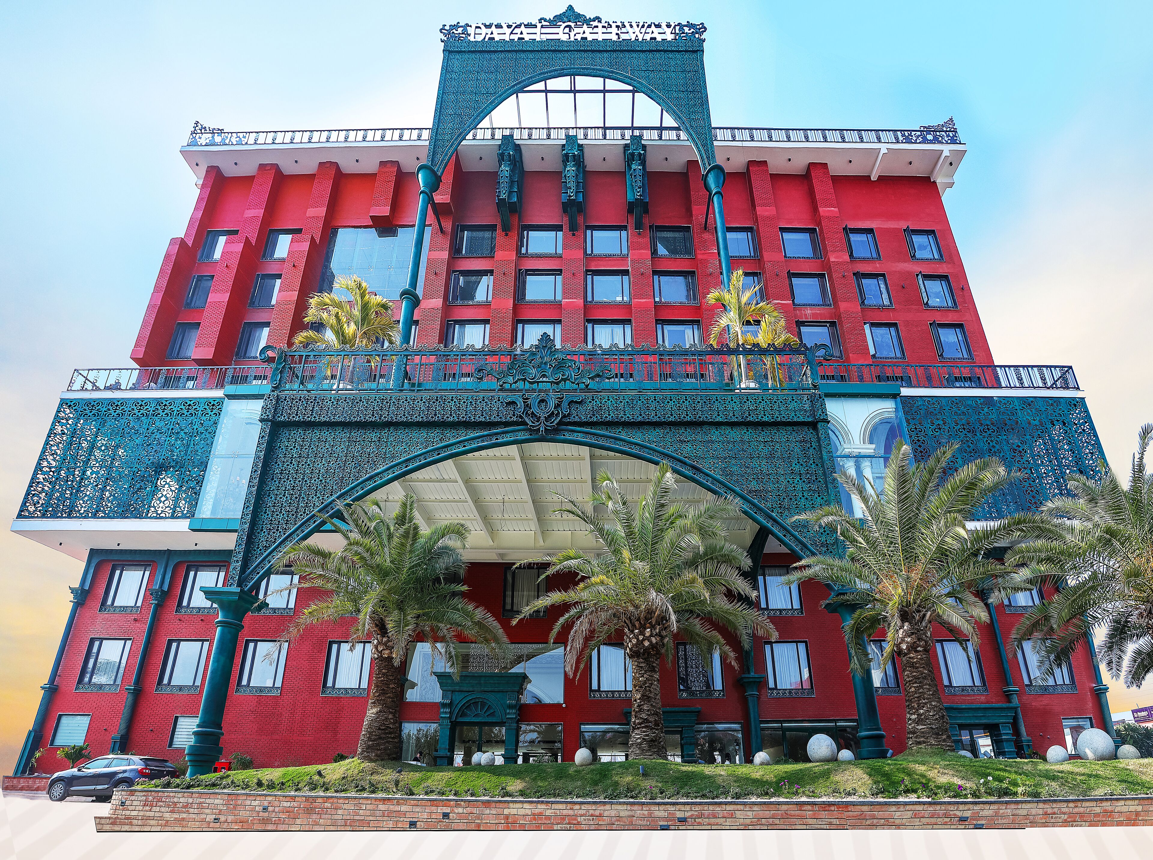 Un edificio rojo con una entrada decorativa y palmeras al frente.
