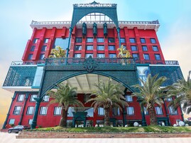 Un edificio rojo con una entrada decorativa y palmeras al frente.