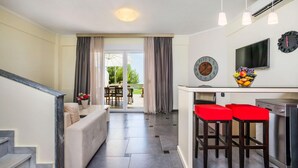 A modern kitchen with a dining area, a sofa, and a staircase. - Sunny Villa in Chaniotis (Kassandra)