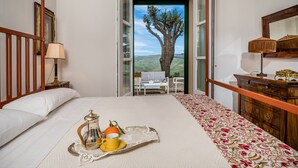 A bedroom with a bed, bedside table, lamp, and a tray with a teapot, cup, and orange. - Principi di Butera 14 (Butera)