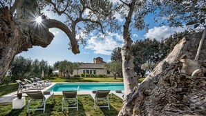 A poolside area with lounge chairs and a clear view of a house in the background. - Principi di Butera 14 (Butera)