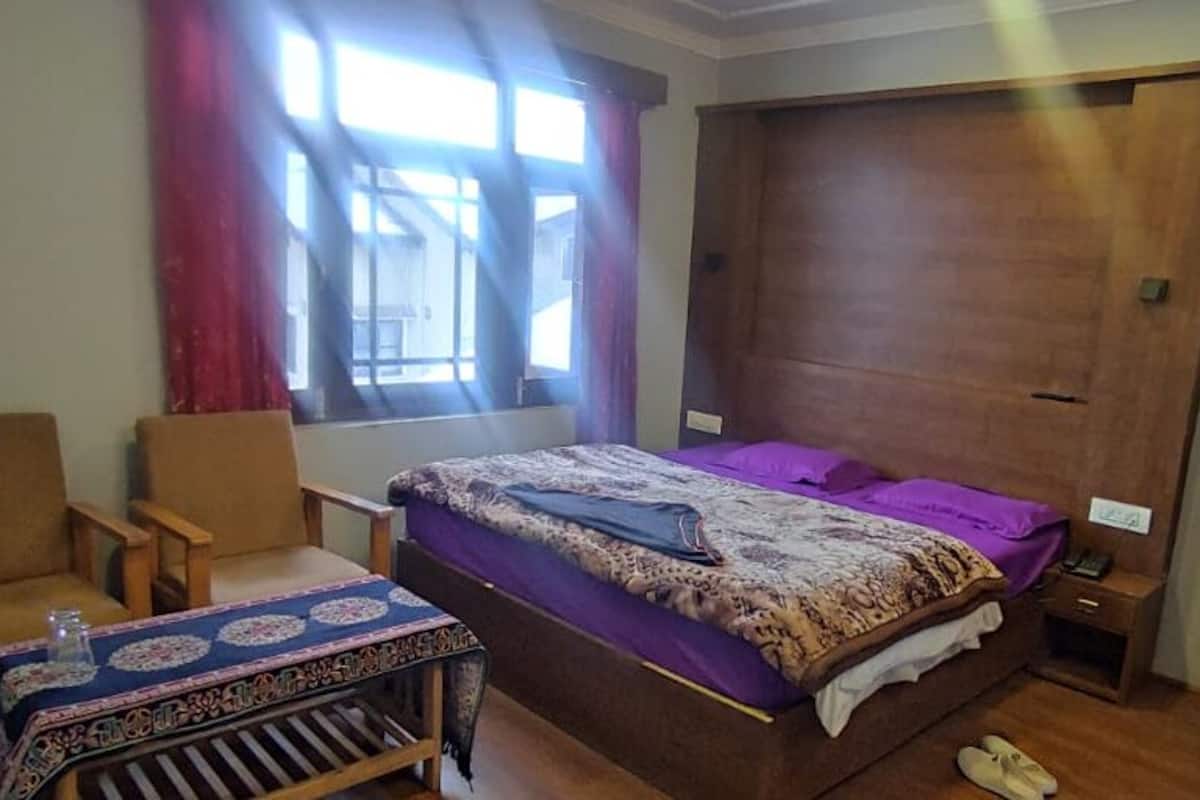 A bedroom with a bed, a chair, a small table, and a wardrobe.