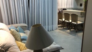 A living room with a sofa, a lamp, and a dining area with chairs and a table.
