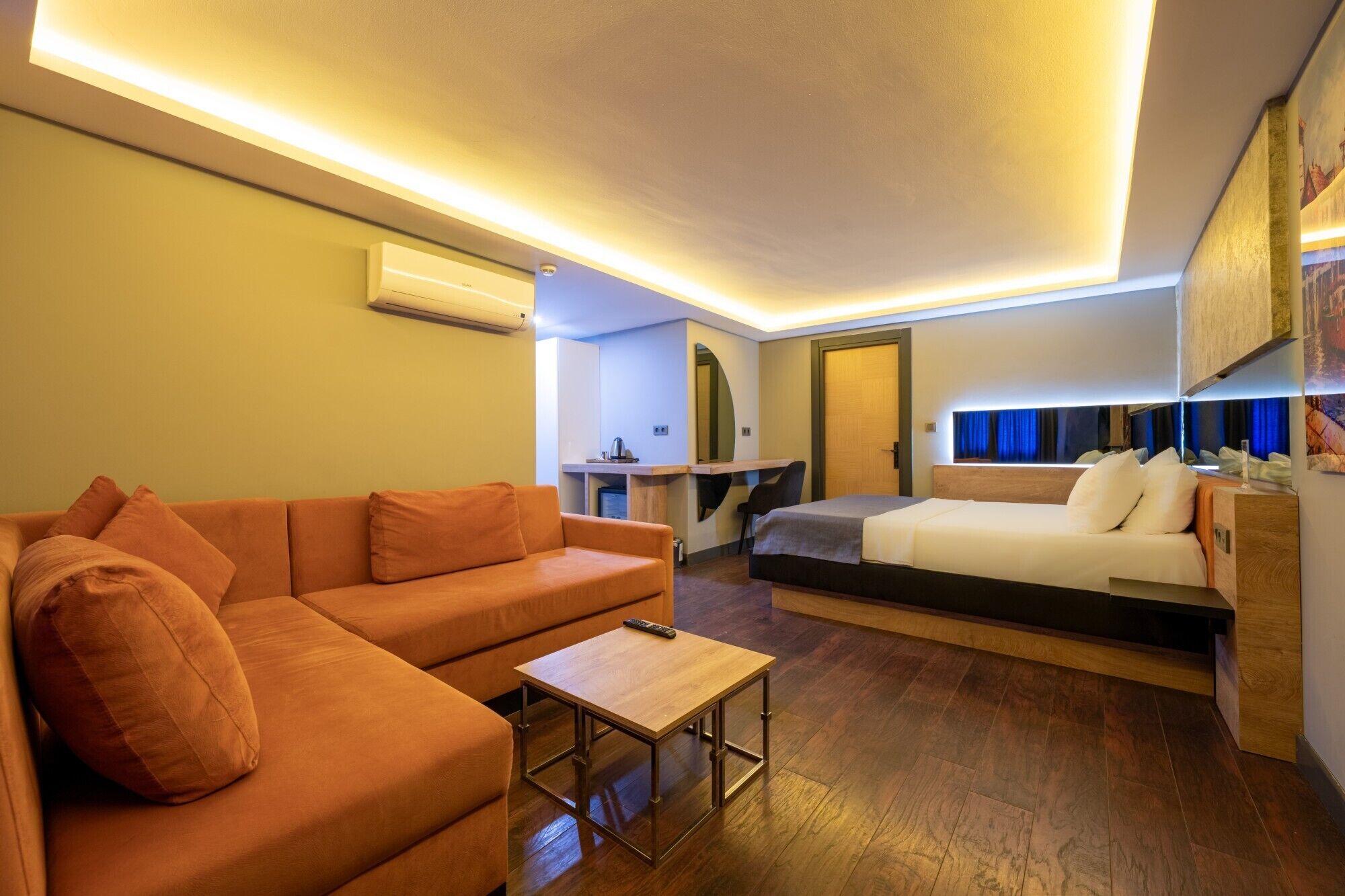Ein modernes Hotelzimmer mit einer Couch, einem kleinen Tisch, einem Bett und einem Schreibtisch.