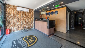Ein Hotel-Empfangsbereich mit Marmorwand, Empfangstresen und digitaler Uhr.