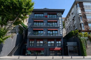 Um edifício de vários andares com um destaque para o letreiro 'Bosphorus', apresentando uma varanda com grades e plantas em vasos.