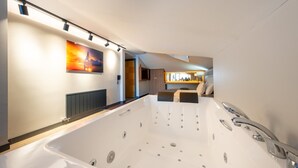 Ein modernes Badezimmer mit einer großen Badewanne, einer Duschkabine und einer Sitzecke mit Blick auf die Stadtlandschaft.