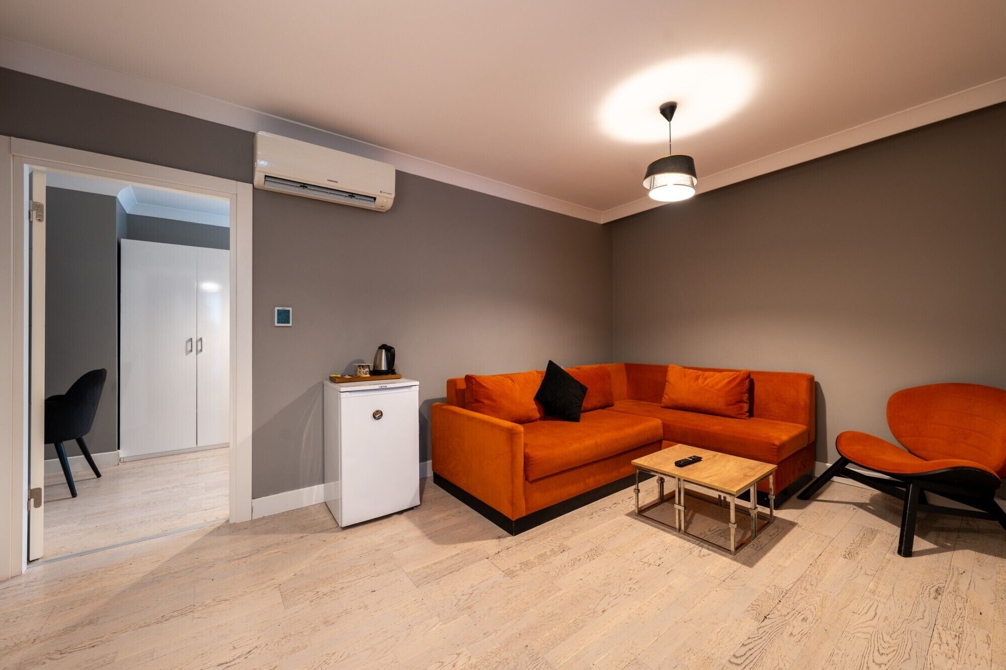A modern living room with a sofa, a coffee table, and a compact refrigerator.