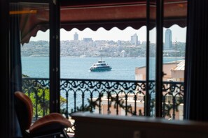 Une vue sur un paysage urbain à travers une fenêtre ornée d’un balcon avec une balustrade.