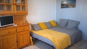 A bedroom with a bed, a wooden cabinet with glass doors, a television, and a painting on the wall.