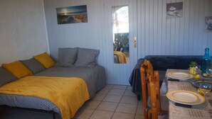 A room with a bed, a sofa, a dining table set with plates and glasses, and a mirror on the door.