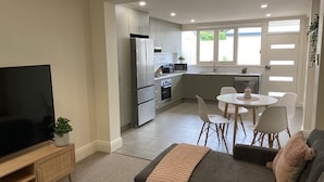 A compact living space with a kitchenette, a dining area, and a seating area with a sofa and chairs.