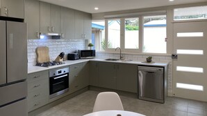 A modern kitchen with grey cabinets, a built-in oven, a microwave, and a dishwasher.
