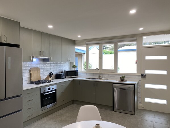A modern kitchen with grey cabinets, a built-in oven, a microwave, and a dishwasher.